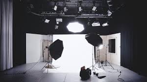 Photo studio hire London with professional lighting equipment, camera on tripod, reflector, and white background studio setup for photography and videography