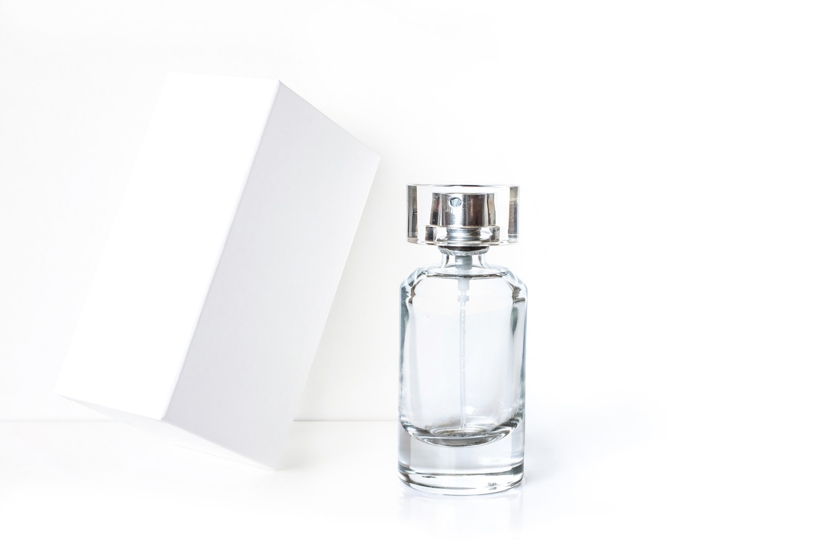 Clear perfume bottle and white packaging on a clean background